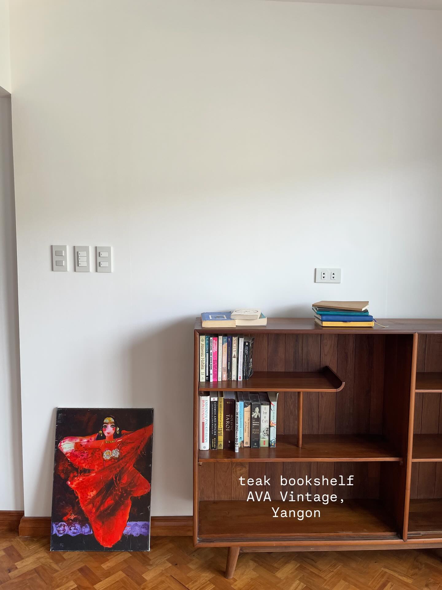 Low teak bookshelf with open shelves against a wall